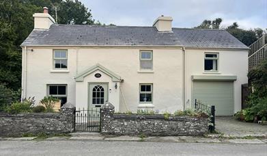 Nestled in a tranquil rural setting, Bridge House Dalby is a picturesque two-story home with a classic white exterior and a grey roof.