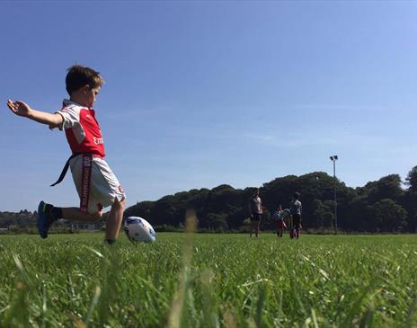 Child kicking a rugby ball