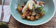 Fillets of fish with local queenies on a plate in the restaurant
