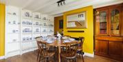 Bridge House Dalby – cozy dining room with wooden table set for six, yellow walls, built-in ceramic display, and bookshelf in pet-friendly self-cateri