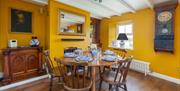 Bridge House Dalby – cozy dining room with round wooden table, yellow walls, vintage wall clock, mirror, and traditional décor in pet-friendly self-ca