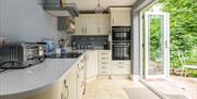 Bridge House Dalby – modern self-catering kitchen with induction hob, double oven, silver toaster, blue and white décor, and access to outdoor seating
