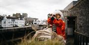 Child in dress-up costume surveying the horizon through a telescope