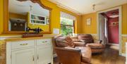 Bridge House Dalby – inviting room with antique sewing machine, leather armchairs, yellow walls, and doorway leading to master bedroom in pet-friendly