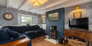 Bridge House Dalby – cozy living room with blue sectional sofa, wood-burning stove, flat-screen TV, and framed painting of SS Viking steamship