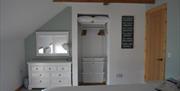 White dressing table containing 7 drawers, hairdryer with light to side, mirror about and bin to left of dressing table, wardrobe hanging space, with