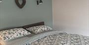 Superking bed in main bedroom with overhead lights and luxury cotton bedding with yacht print in sea green, blue and white.