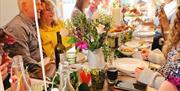 Party with guests sat at a long table with food and decorations.